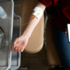 Person receiving IV therapy while holding a smartphone, illustrating the future of mobile IV therapy in modern wellness care.