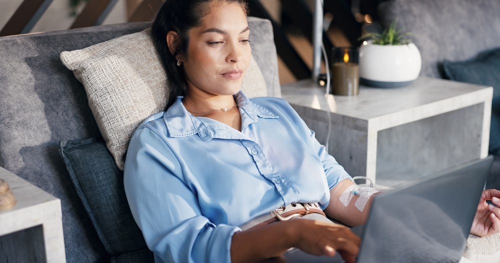 Woman relaxing during an iron infusions session while working on a laptop at Amani Health and Wellness