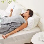 Woman resting in bed receiving IV therapy for illness with drip stand visible at home