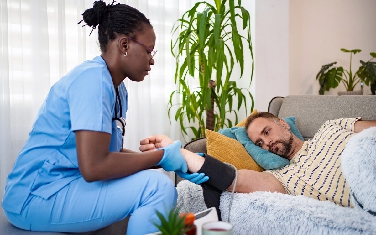 Concierge nurse monitoring blood pressure during post-surgical recovery at home visit