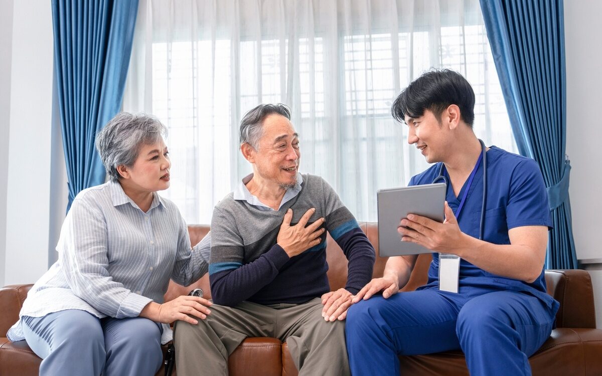 Licensed concierge nurse reviewing care information with an older couple on a tablet during a home visit