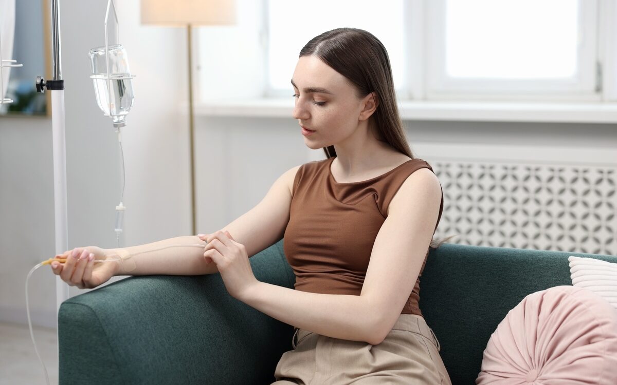 How often do you need iron infusions: woman receiving an IV infusion while relaxing at home